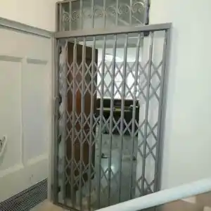 درب و حفاظ آکاردئونی نصب&zwnj;شده روی دیوار در کرمان